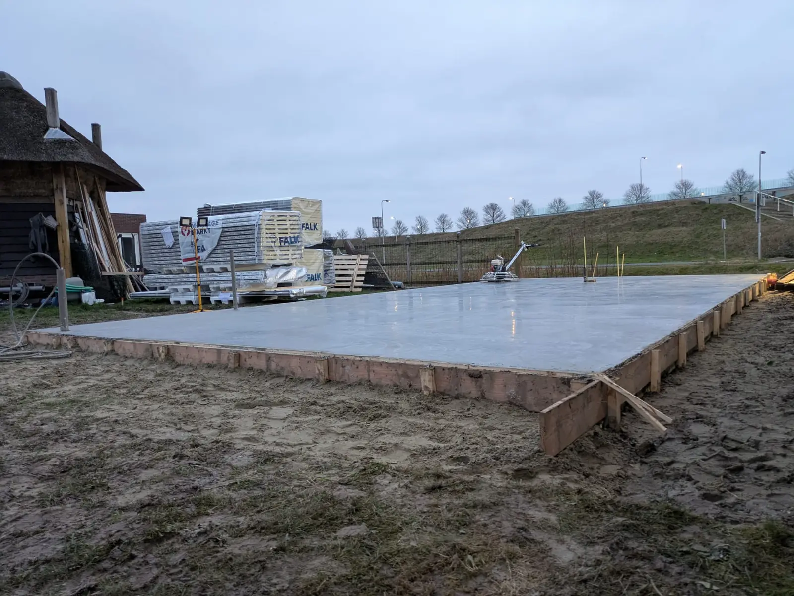 Lange gevlinderde betonvloer naast een rietgedekte schuur