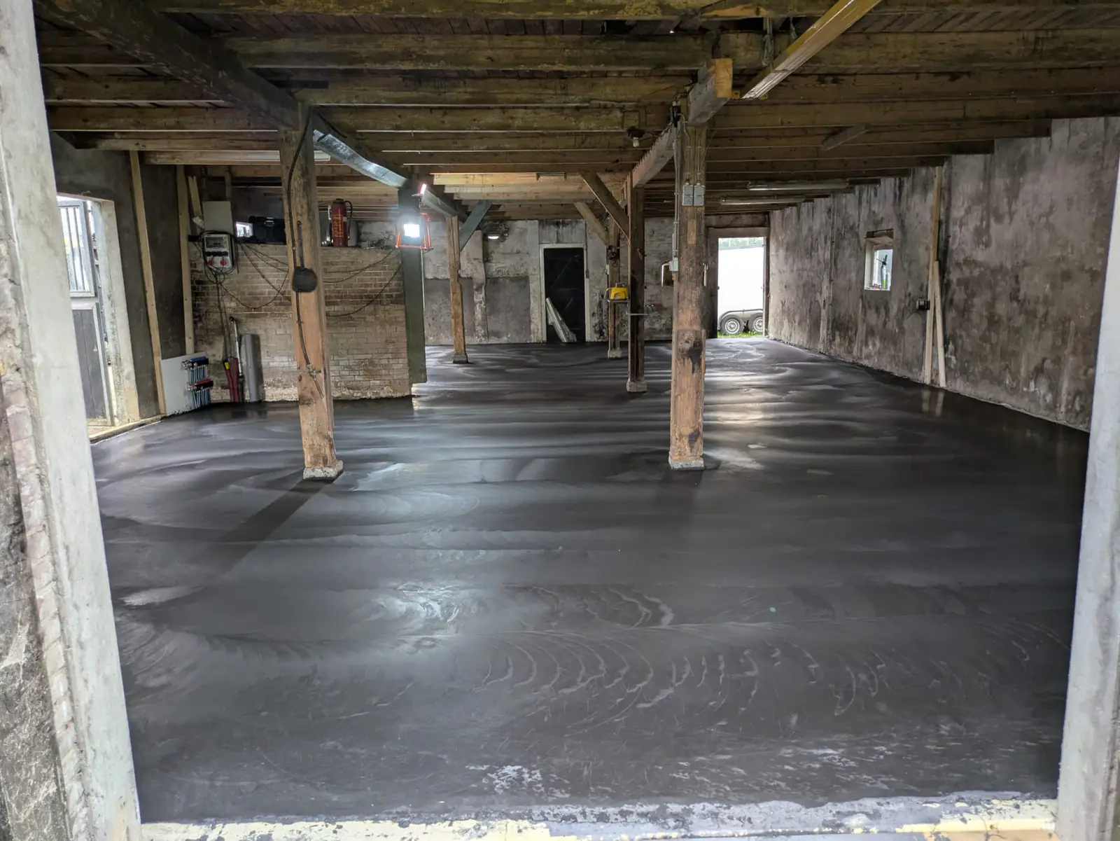 Nieuwe betonvloer gestort in een bestaande schuur met houten stijlen