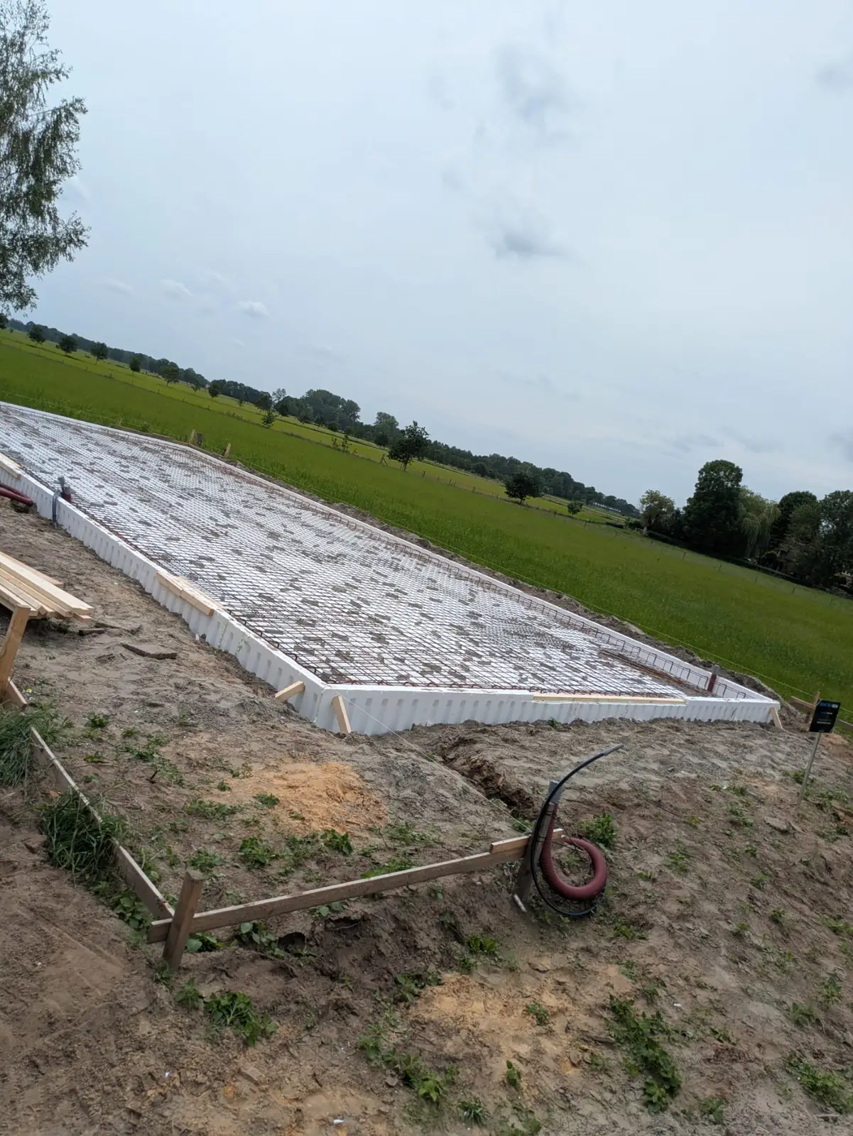 Isolatiebekisting met wapening voor een fundering langs een weiland